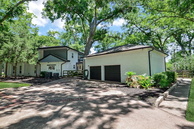 view of home's exterior featuring decorative driveway, brick siding, central AC unit, fence, and an outdoor structure