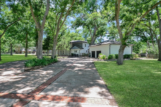 view of front of home featuring an outbuilding, an attached garage, a front yard, fence, and driveway