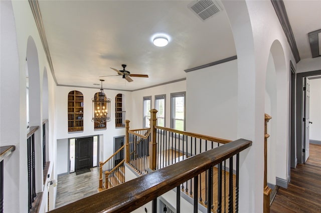 hall with visible vents, dark wood-style flooring, crown molding, an upstairs landing, and a chandelier