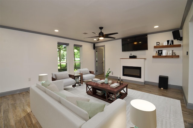 living area with recessed lighting, baseboards, wood finished floors, and a glass covered fireplace