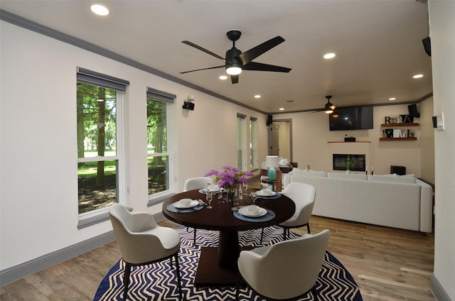 dining area featuring recessed lighting, a glass covered fireplace, crown molding, and wood finished floors