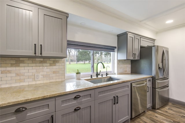 kitchen with dark wood-style floors, gray cabinets, appliances with stainless steel finishes, ornamental molding, and a sink