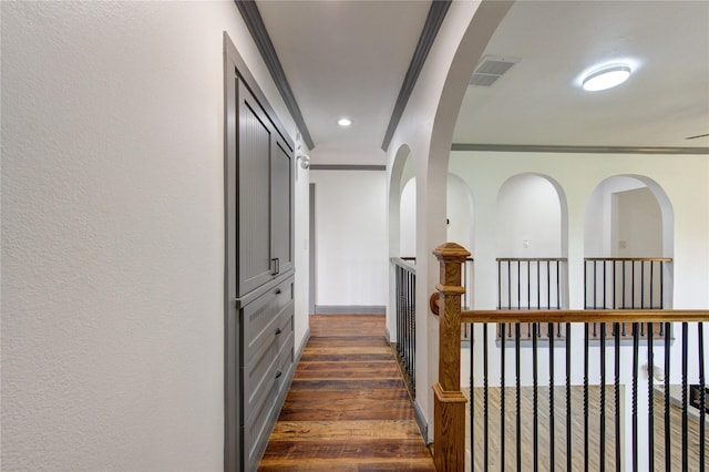 hallway with a textured wall, dark wood-style flooring, visible vents, baseboards, and crown molding