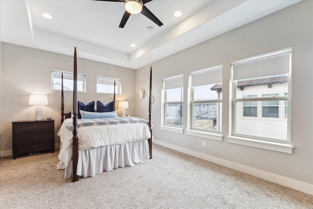 bedroom with a tray ceiling, carpet flooring, and baseboards