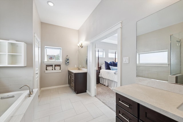 ensuite bathroom with vanity, baseboards, tiled shower, a bath, and ensuite bath