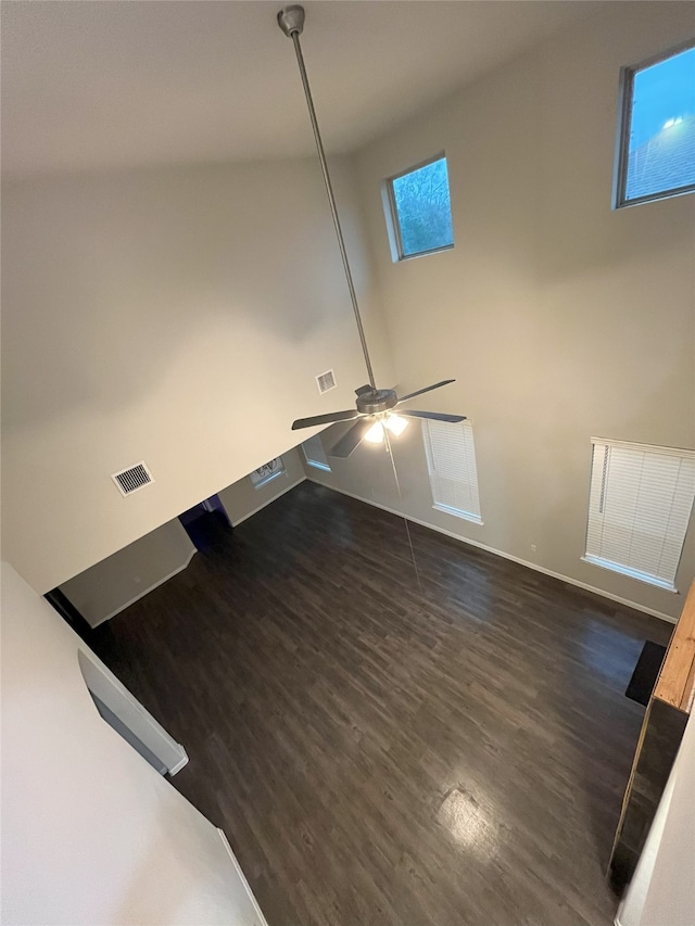 interior space featuring baseboards, a high ceiling, visible vents, and dark wood-type flooring