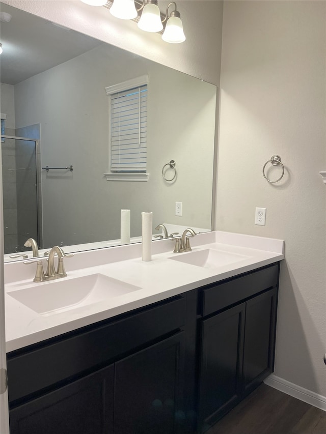 full bathroom featuring double vanity, a stall shower, a sink, and wood finished floors