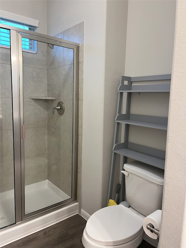 full bath with a stall shower, baseboards, toilet, and wood finished floors