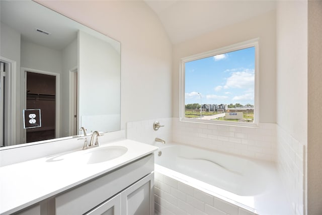 bathroom featuring lofted ceiling, visible vents, a garden tub, and vanity