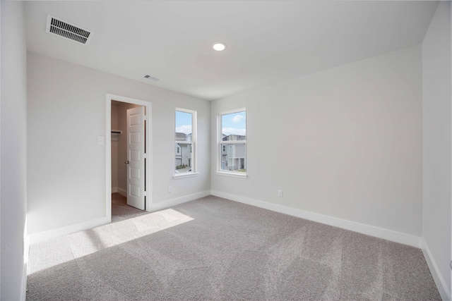 unfurnished room with carpet, visible vents, and baseboards