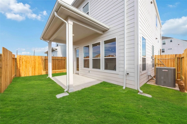 back of house featuring a patio area, a fenced backyard, central AC, and a yard