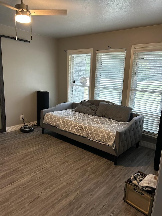 bedroom with ceiling fan, multiple windows, and wood finished floors