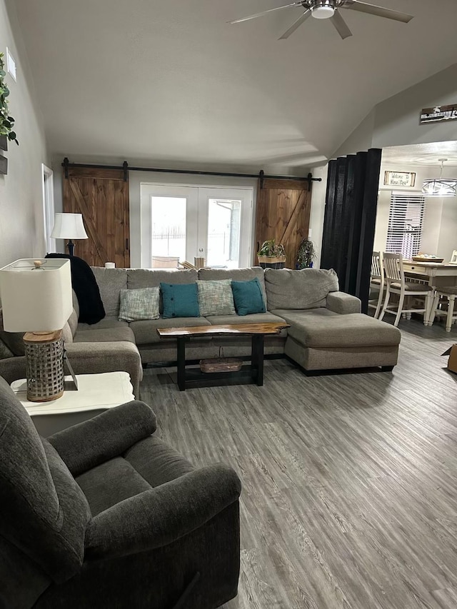 living area with lofted ceiling, a barn door, a ceiling fan, and wood finished floors