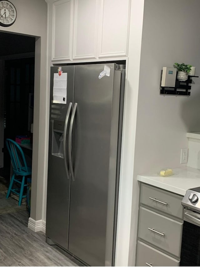 kitchen with light countertops, stainless steel refrigerator with ice dispenser, light wood-style flooring, and gray cabinetry