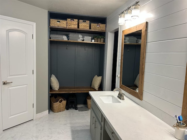 mudroom with marble finish floor, a sink, and wooden walls