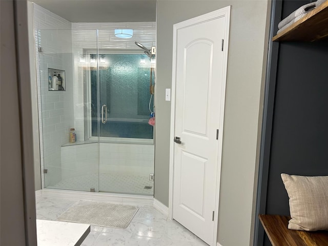 full bath featuring a stall shower, marble finish floor, and baseboards