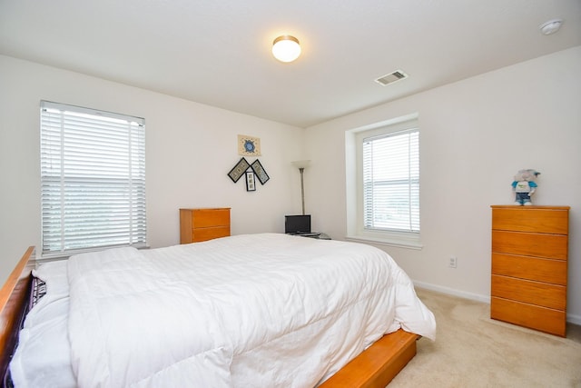 bedroom featuring baseboards, visible vents, and light colored carpet