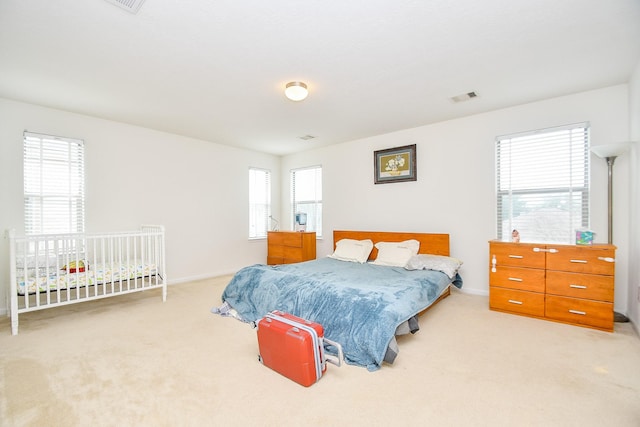 bedroom with baseboards, visible vents, and light colored carpet