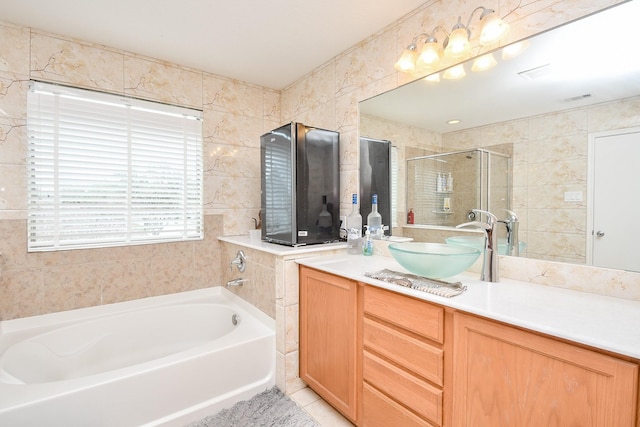 bathroom featuring a stall shower, a bath, tile patterned floors, vanity, and tile walls