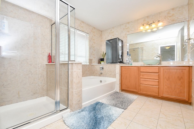 bathroom featuring tile walls, vanity, a shower stall, tile patterned flooring, and a bath