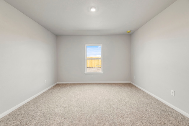 carpeted empty room featuring baseboards