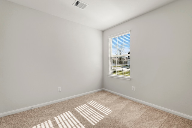 carpeted spare room featuring baseboards and visible vents