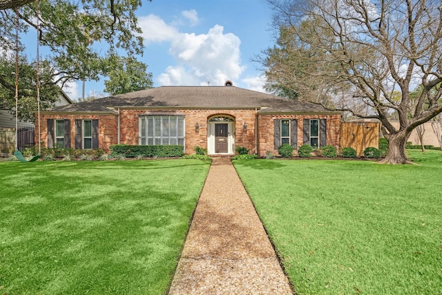 ranch-style home featuring brick siding, a front yard, and fence