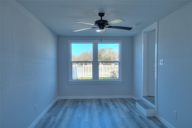 empty room featuring baseboards, ceiling fan, and light wood-style floors