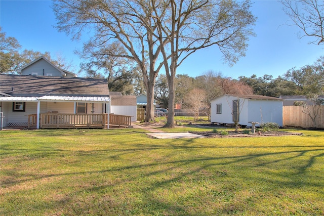 view of yard featuring a shed, an outdoor structure, a wooden deck, and fence