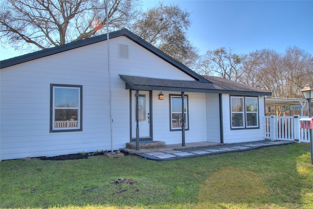 back of property with a yard, a shingled roof, and fence