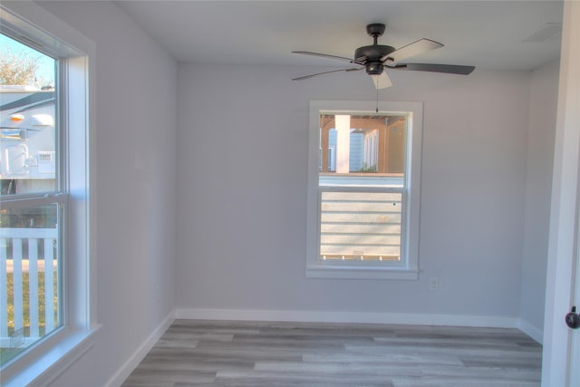 unfurnished room with visible vents, plenty of natural light, baseboards, and wood finished floors