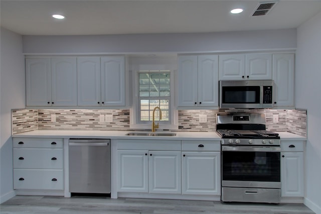 kitchen with light countertops, visible vents, appliances with stainless steel finishes, white cabinetry, and a sink