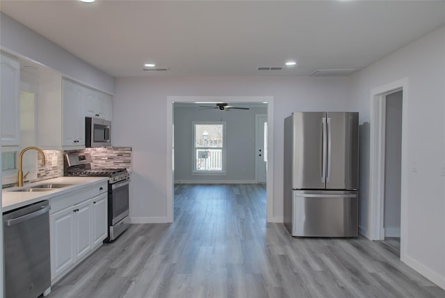 kitchen with tasteful backsplash, light countertops, appliances with stainless steel finishes, white cabinets, and a sink