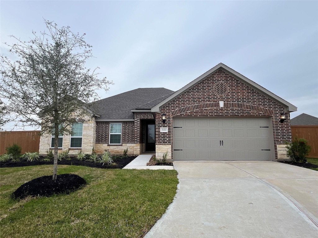 view of front of house featuring concrete driveway, stone siding, roof with shingles, a front lawn, and brick siding