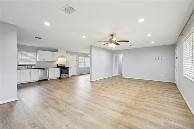 unfurnished living room featuring recessed lighting, visible vents, a sink, and light wood finished floors