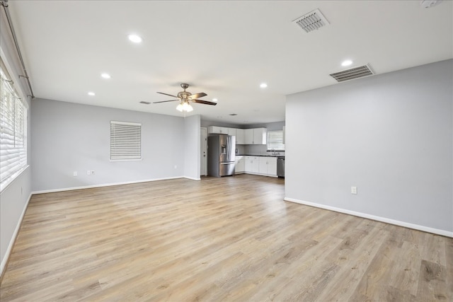 unfurnished living room featuring a wealth of natural light, light wood-style flooring, and visible vents