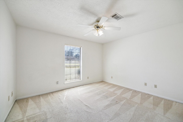 unfurnished room with ceiling fan, a textured ceiling, visible vents, and light colored carpet