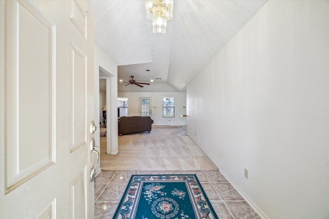 carpeted entrance foyer featuring lofted ceiling, baseboards, ceiling fan with notable chandelier, and tile patterned floors