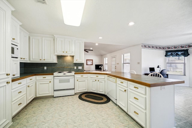 kitchen with white appliances, a peninsula, white cabinetry, backsplash, and recessed lighting