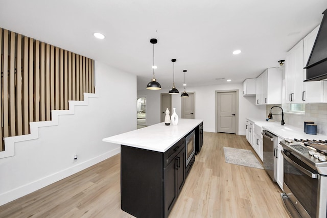 kitchen featuring light wood finished floors, a kitchen island, white cabinets, and stainless steel appliances
