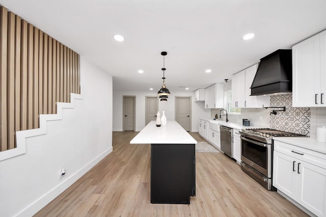 kitchen featuring stainless steel appliances, custom exhaust hood, a sink, and light wood finished floors