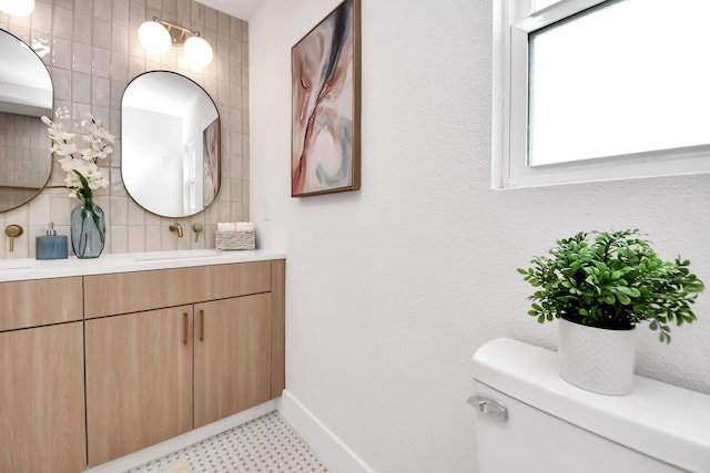 bathroom with vanity, toilet, tile patterned floors, baseboards, and backsplash