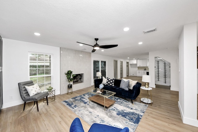 living area featuring baseboards, a ceiling fan, light wood finished floors, and visible vents