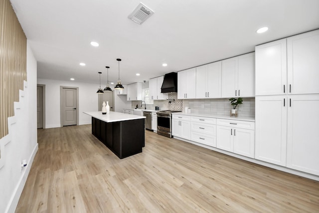 kitchen featuring visible vents, appliances with stainless steel finishes, light countertops, premium range hood, and light wood-style floors