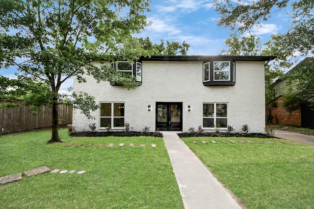 view of front of home with fence, french doors, a front lawn, and brick siding