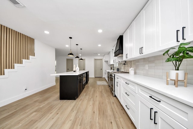 kitchen with light countertops, light wood-style flooring, premium range hood, stainless steel appliances, and visible vents