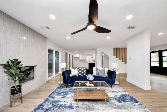 living room with visible vents, stairs, ceiling fan, and light wood-type flooring