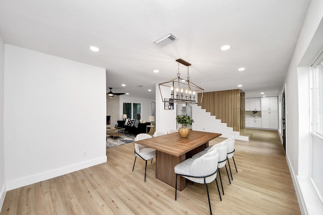 dining room featuring stairway, baseboards, light wood-style flooring, and visible vents