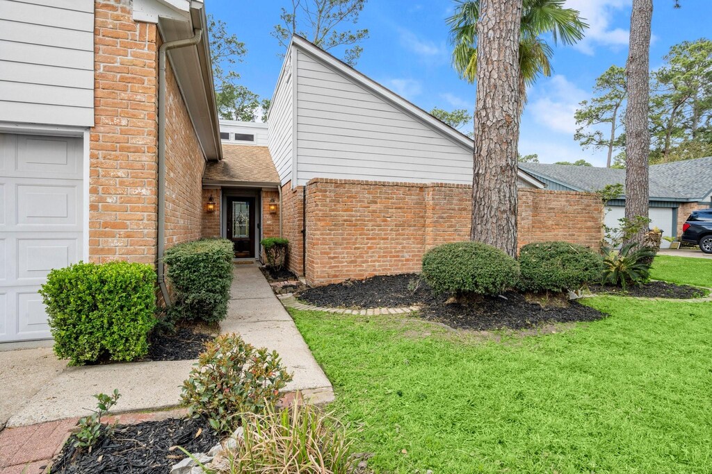 17807 Mellow Ridge Dr, Spring, TX 77379 - view of front of home with brick siding, a front yard, and an attached garage