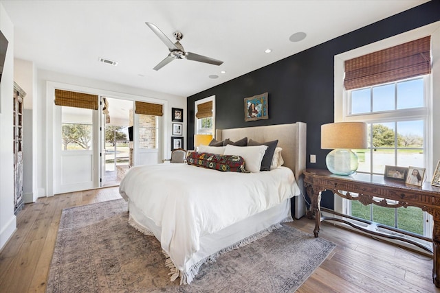 bedroom featuring an accent wall, multiple windows, and light wood-type flooring